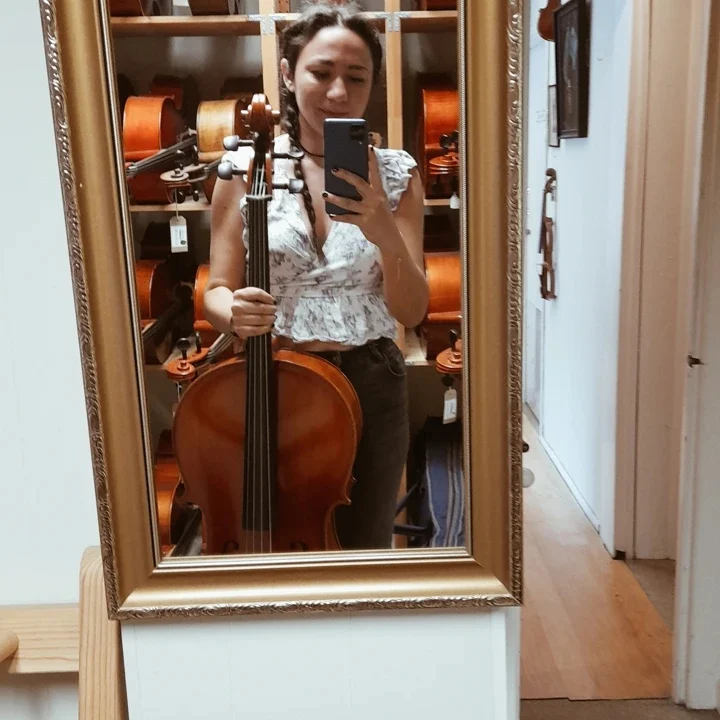 Brittney Pilarcik holding a cello inside the family music shop